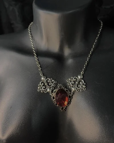 Gargantilha vitoriana vermelha com grande cristal central facetado e laterais ornamentais prateadas.